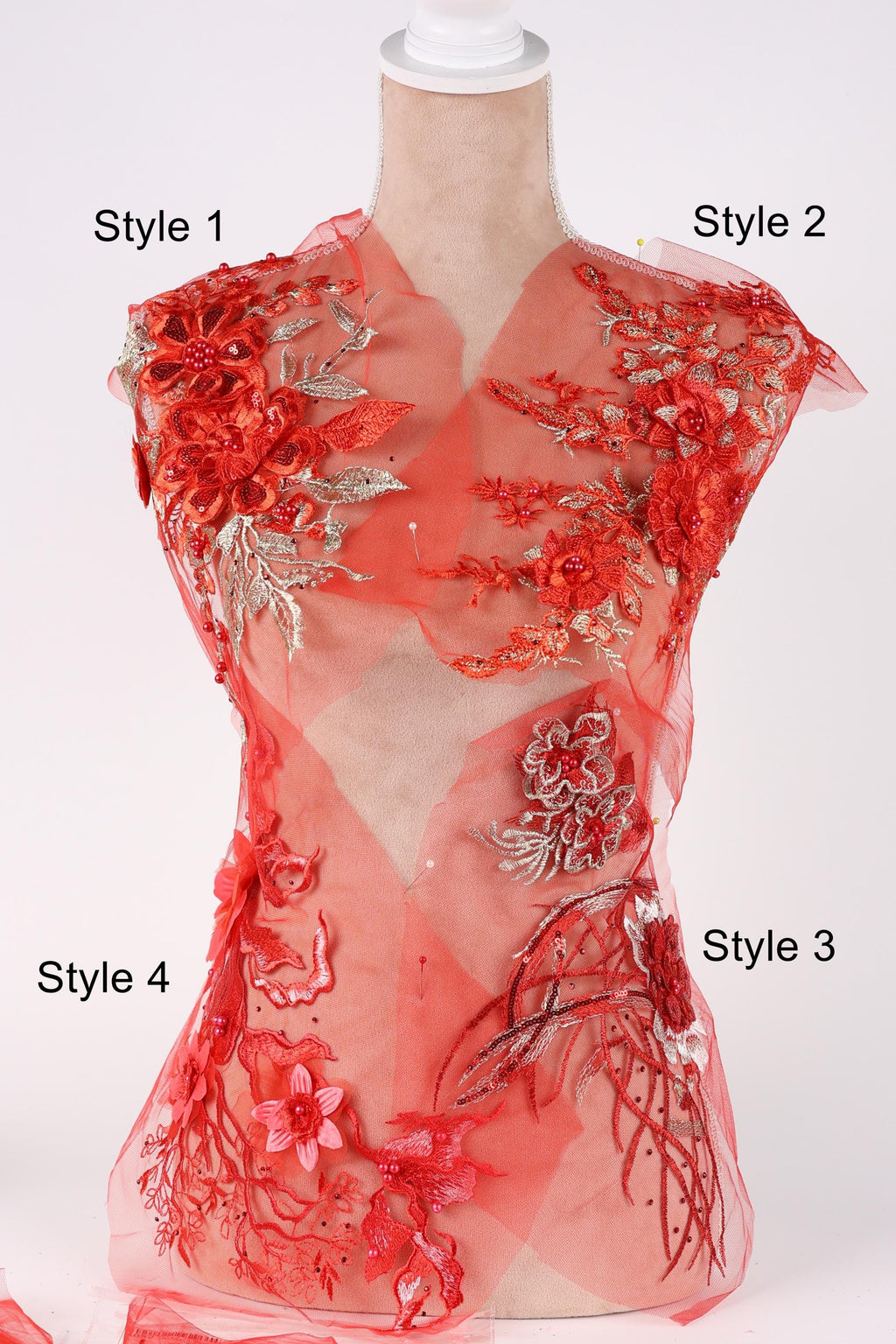 A mannequin wearing a red dress with intricate floral embroidery and floral appliques.