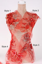 A mannequin wearing a red dress with intricate floral embroidery and floral appliques.