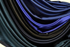 a close-up view of a pile of various colored satin fabric, including shades of blue, black, and green.