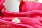 a close-up view of a vibrant pink satin fabric, with a small white label or emblem placed on it.