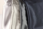 a close-up view of four different colored satin fabrics, with a focus on the color gradient from light to dark.