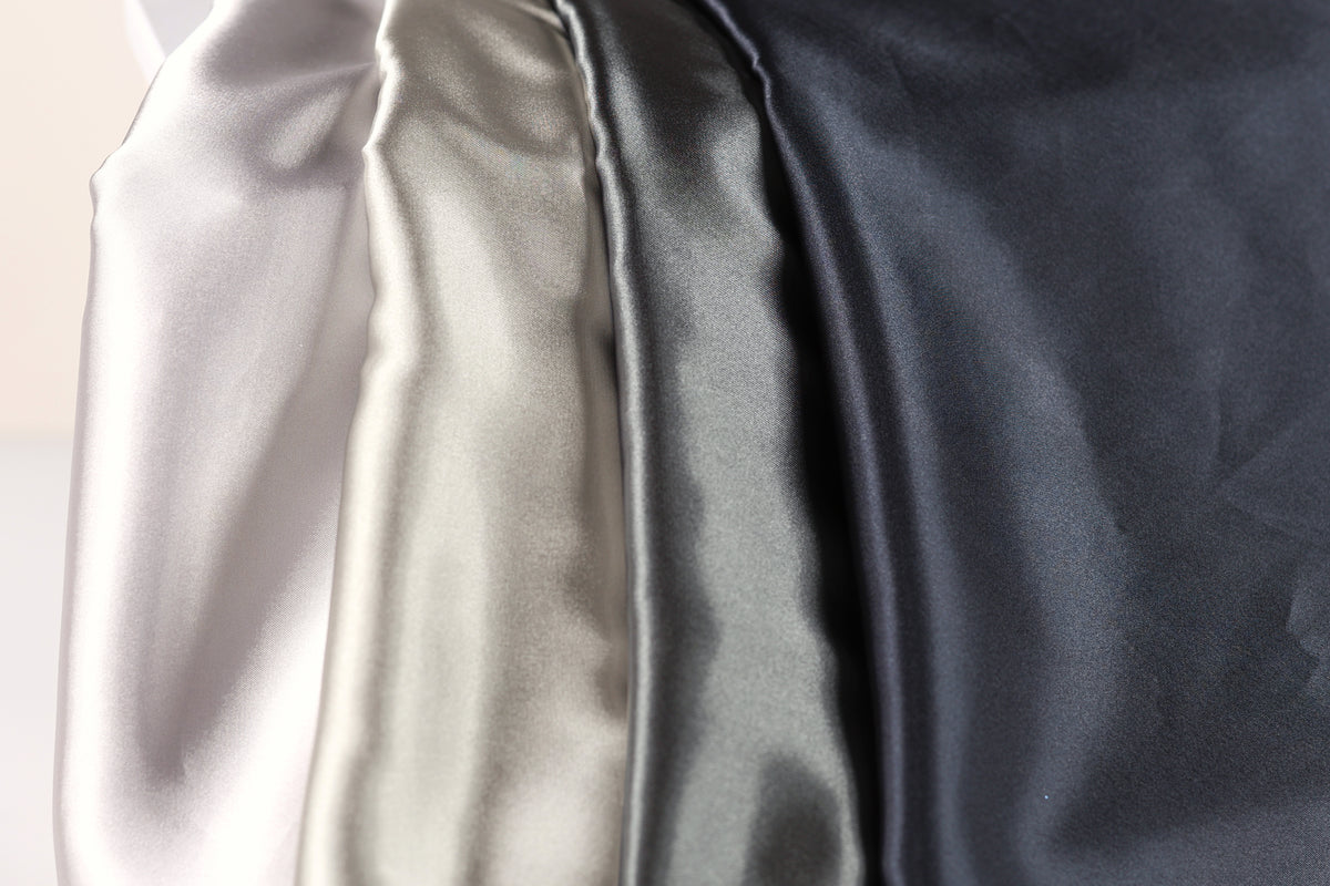 a close-up view of four different colored satin fabrics, with a focus on the color gradient from light to dark.