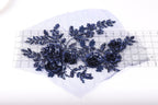 a close-up view of a piece of fabric with a floral design, including blue sequin flowers and leaves.
