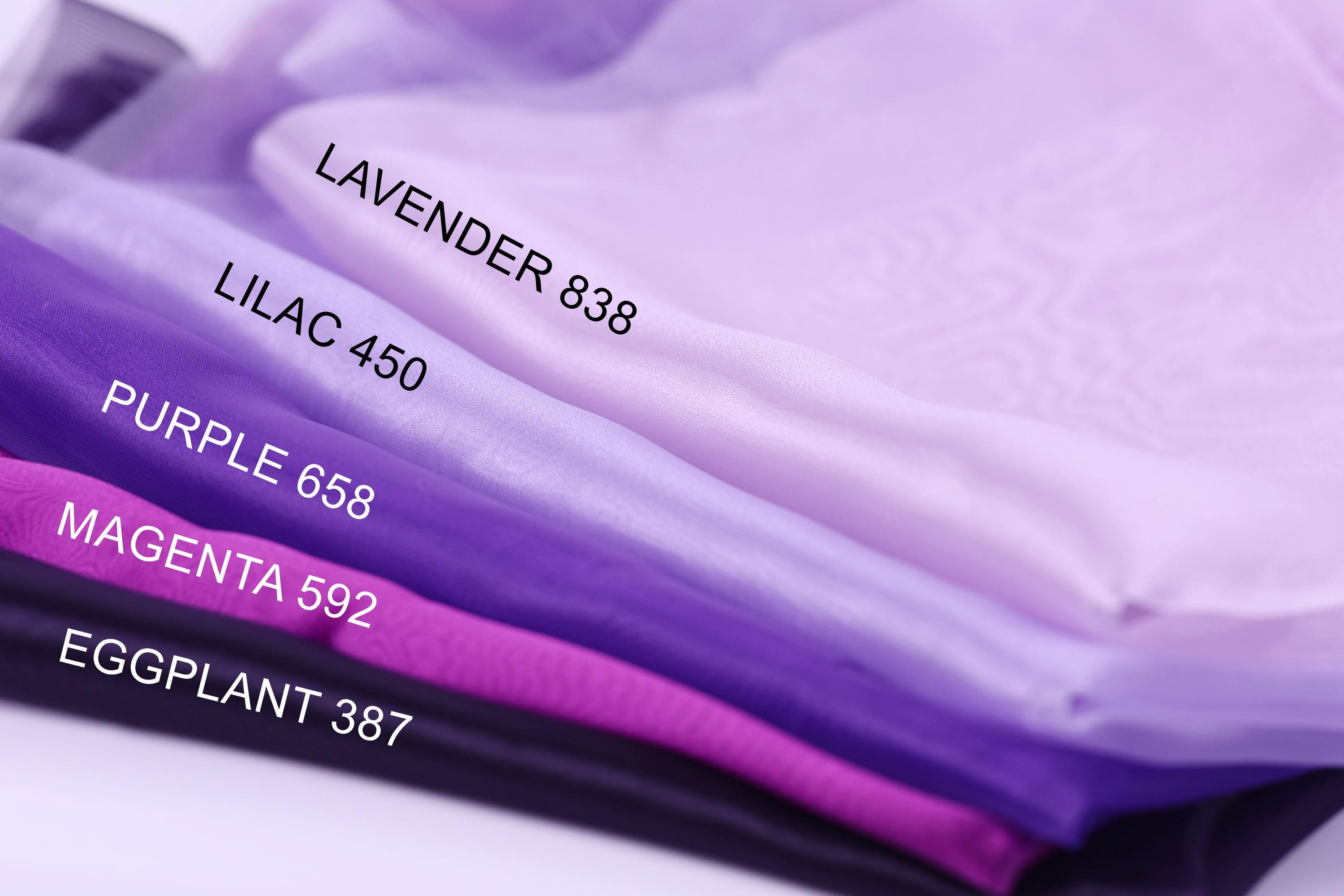 a close-up view of a collection of fabric swatches in various shades of purple, including lavender, lilac, purple, magenta, and eggplant.