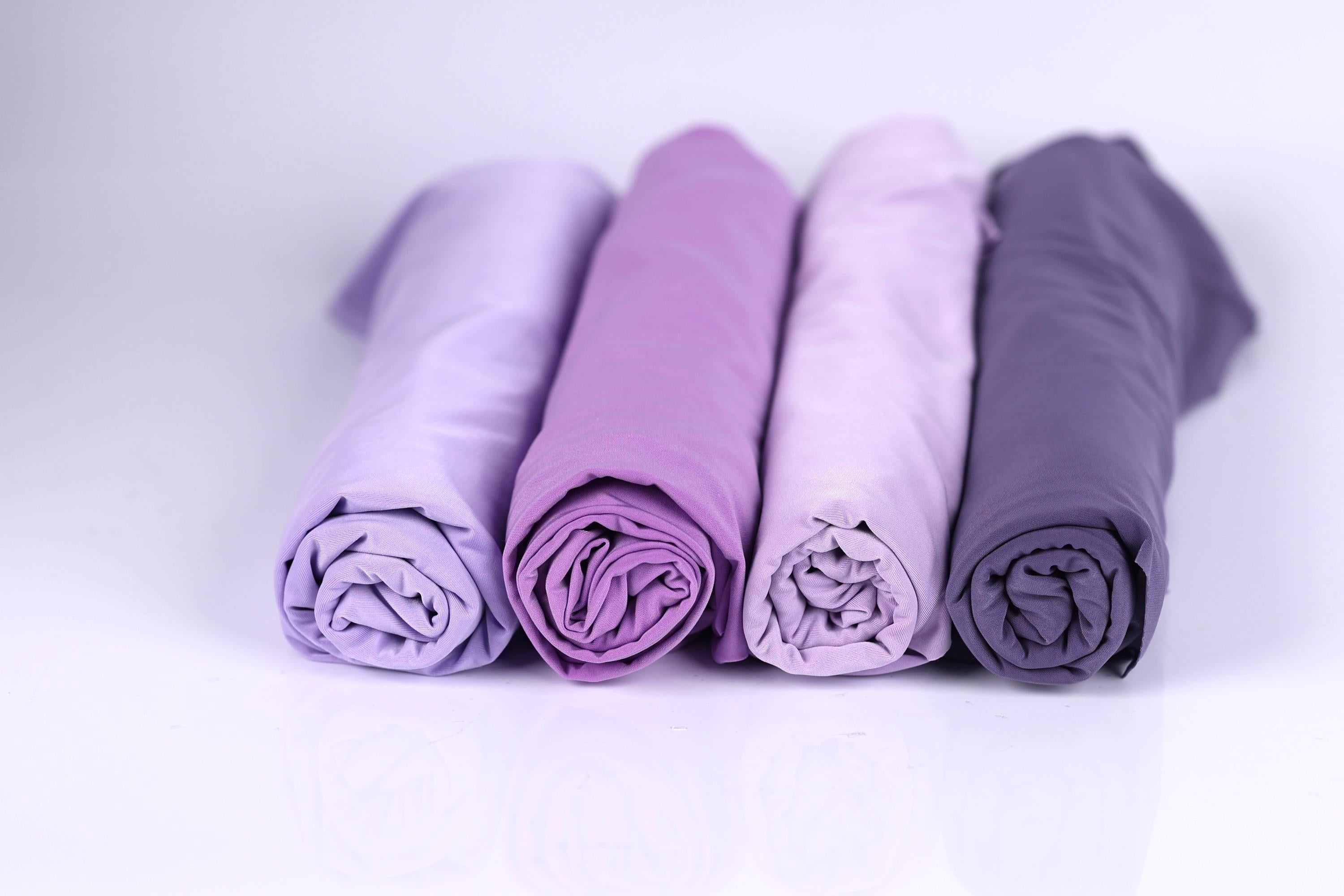 Four rolled-up fabric pieces in different shades of purple are arranged in a row on a white background.