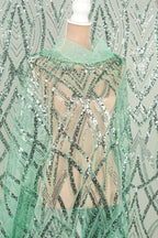 A mannequin wearing a green sequin dress with a sheer overlay.