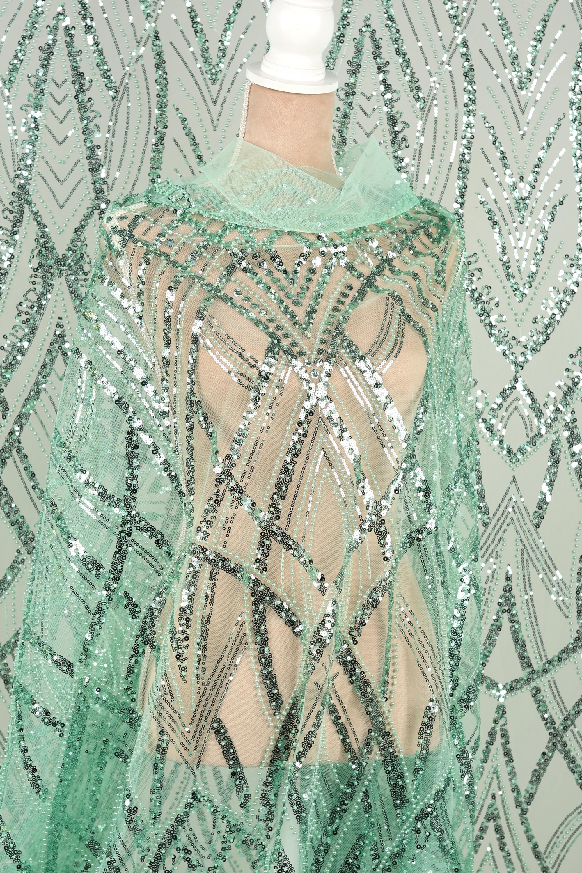A mannequin wearing a green sequin dress with a sheer overlay.