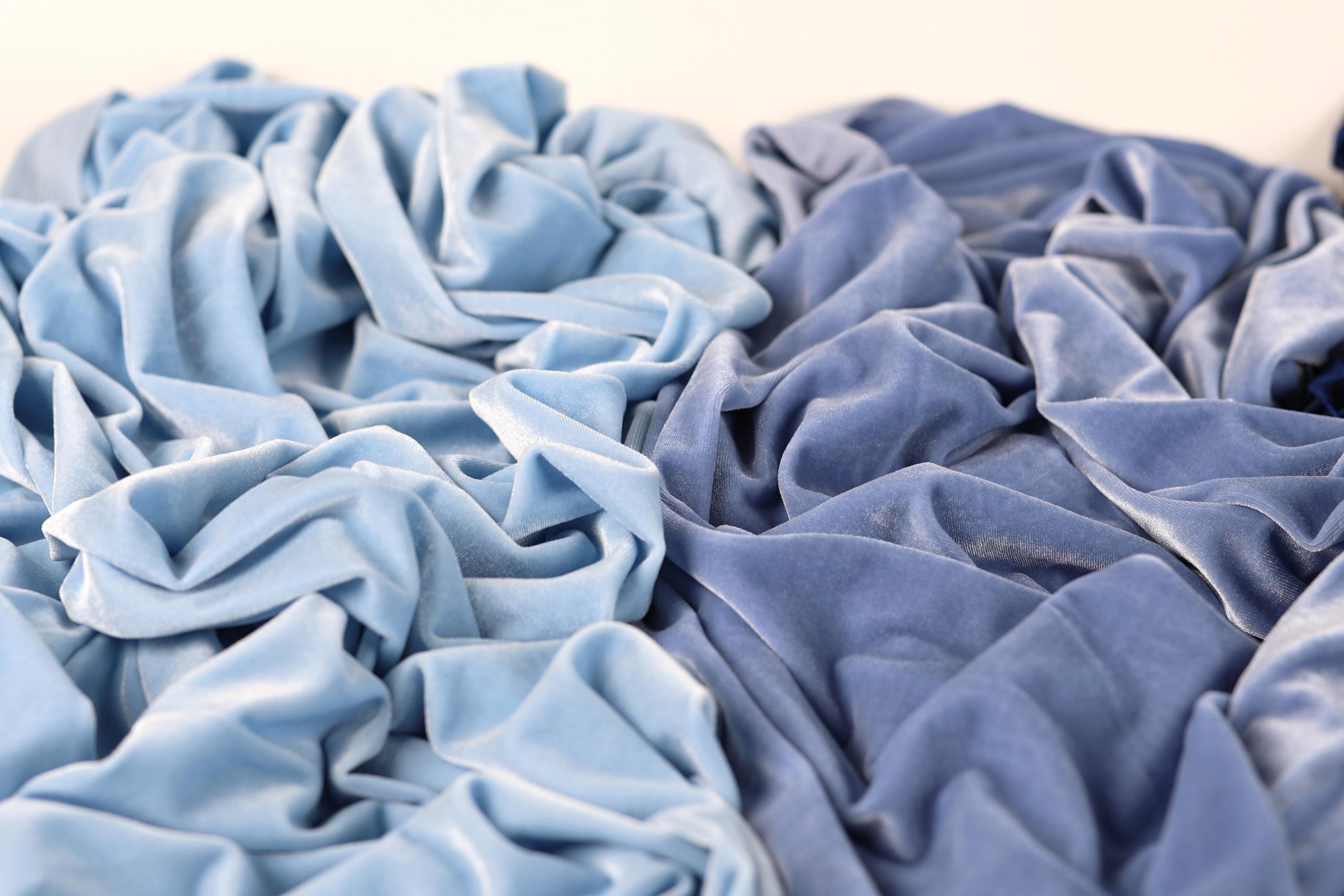 a close-up view of crumpled blue and light blue fabric, with the light blue fabric appearing more vibrant and the blue fabric appearing more faded.