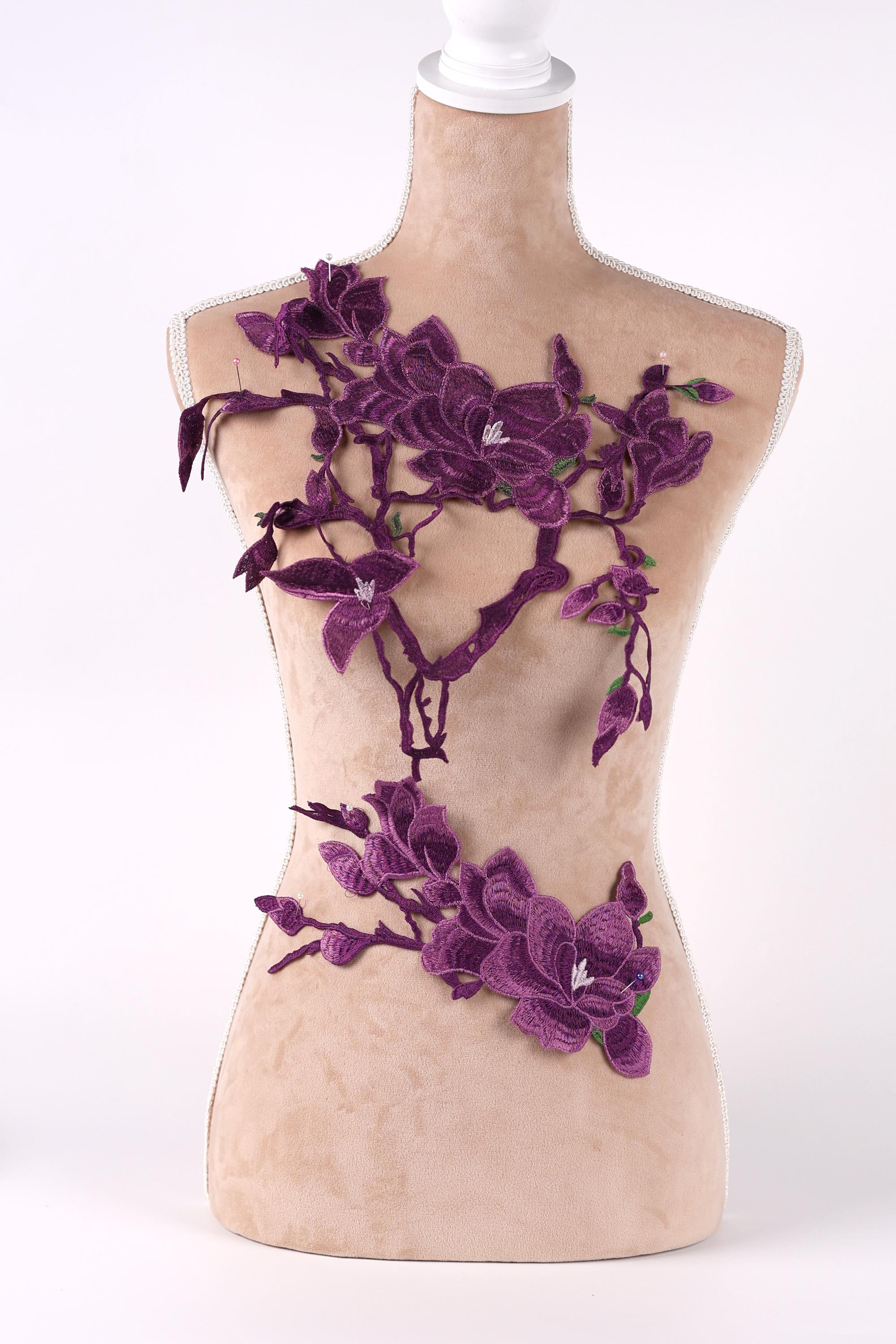 A mannequin torso with purple floral embroidery on it.