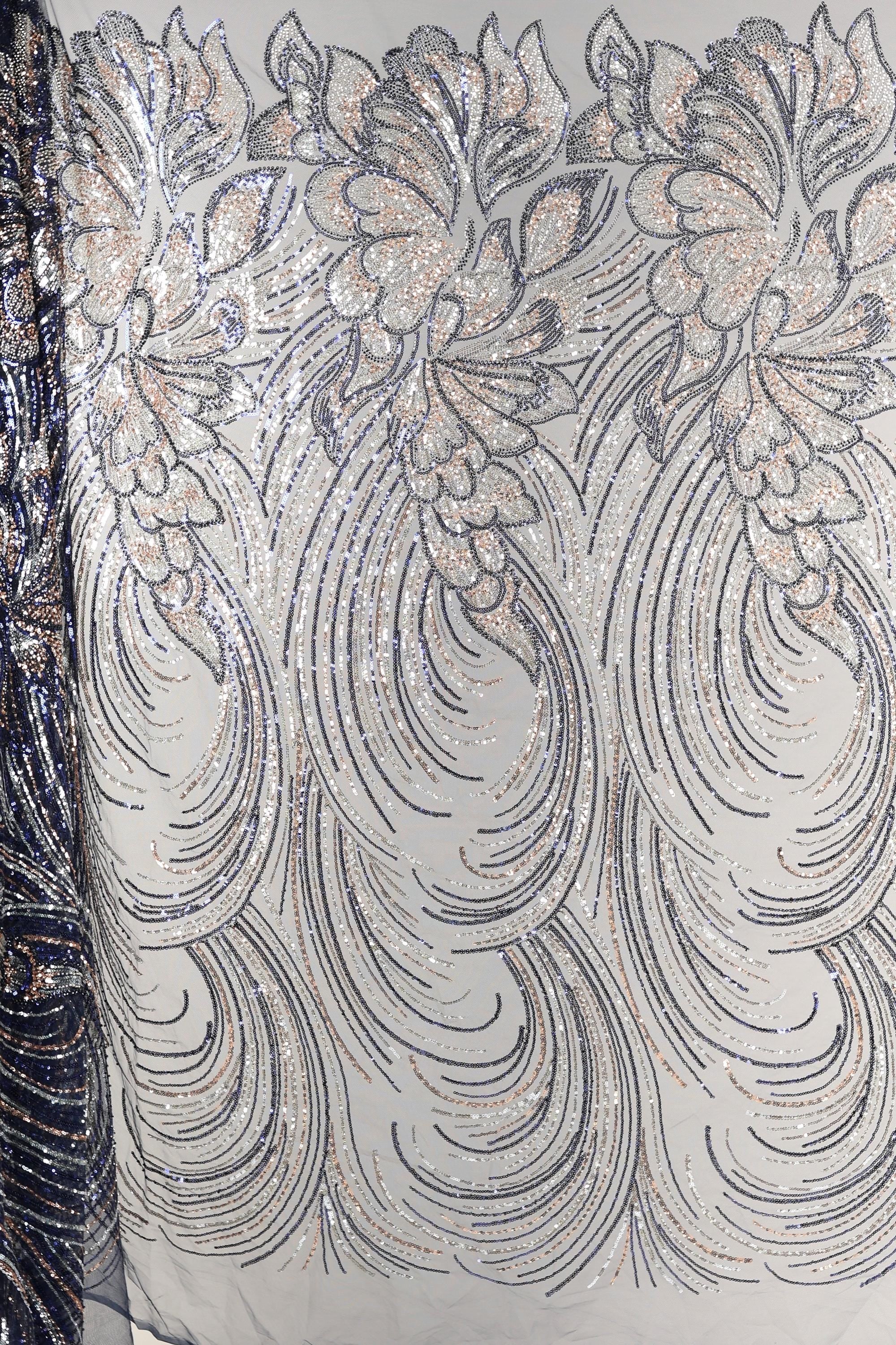 a close-up view of a fabric with a repeating pattern of silver and black sequin designs. The pattern consists of various shapes and swirls, creating a visually striking and intricate design. The fabric appears to be a light-colored material, possibly cotton or linen, with the silver and black sequins adding a touch of sparkle and elegance to the overall appearance.