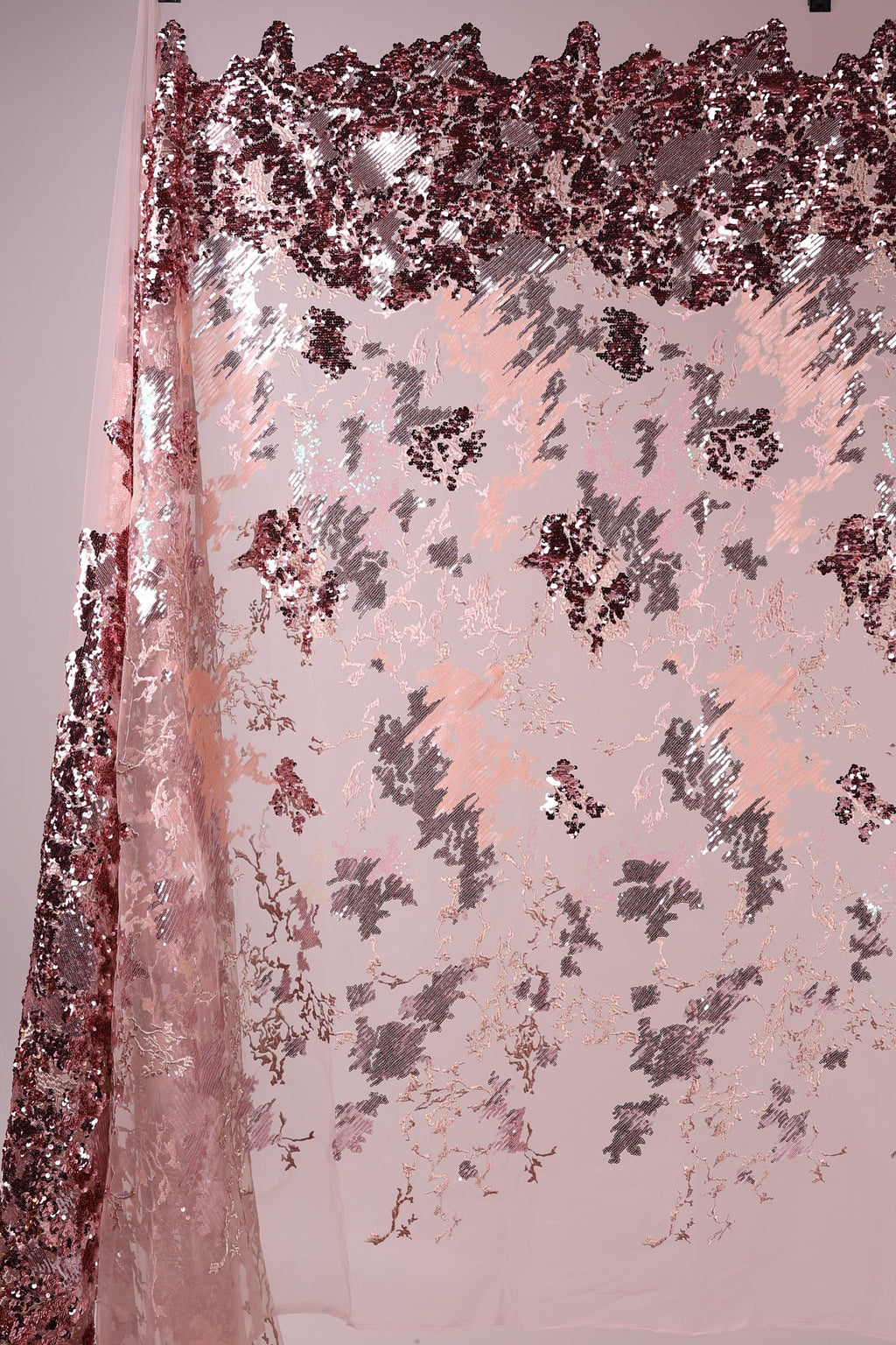 a pink and red sequin fabric with a floral pattern, creating a visually striking and textured appearance.