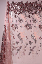 a pink and red sequin fabric with a floral pattern, creating a visually striking and textured appearance.