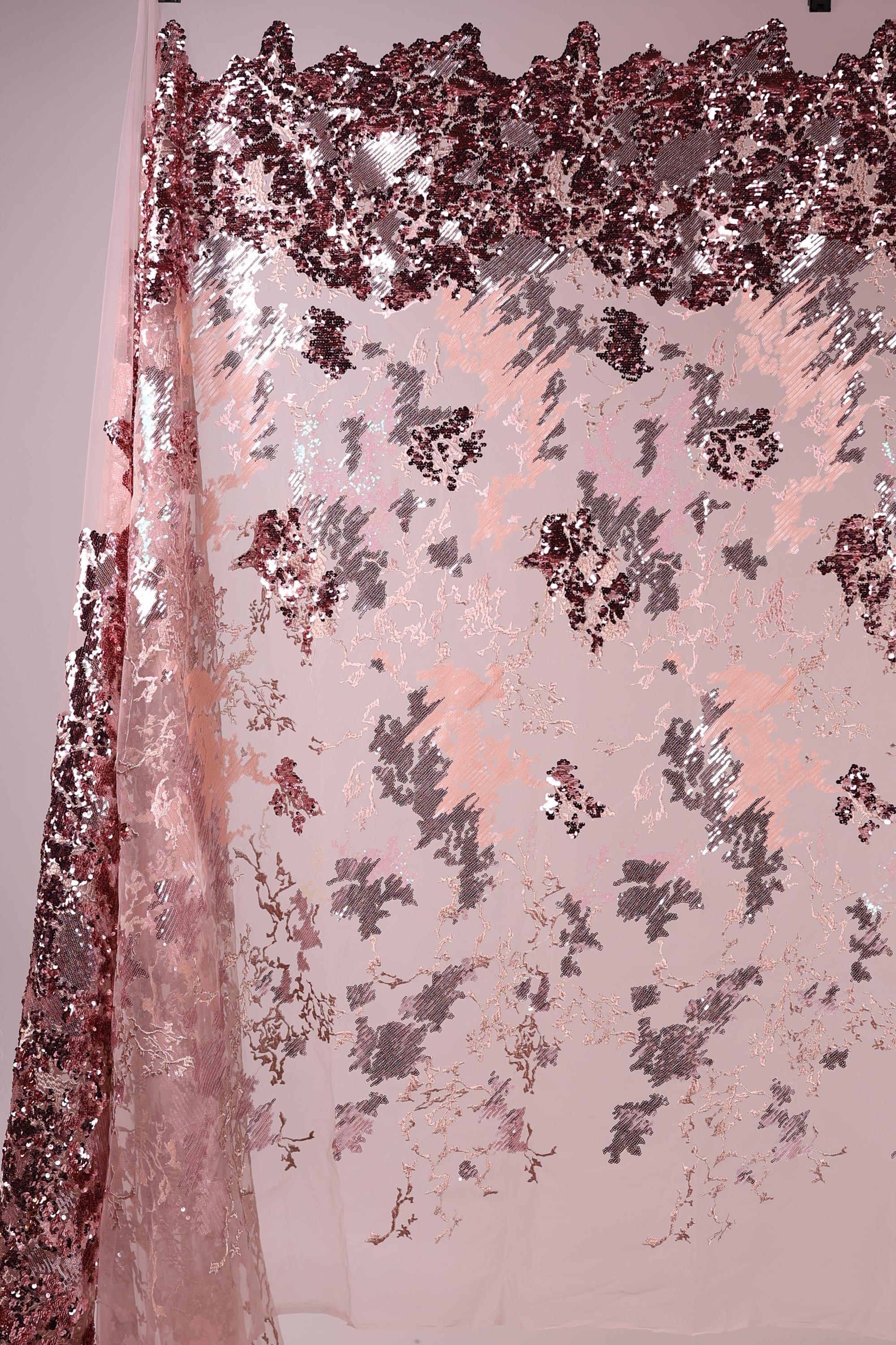 a pink and red sequin fabric with a floral pattern, creating a visually striking and textured appearance.