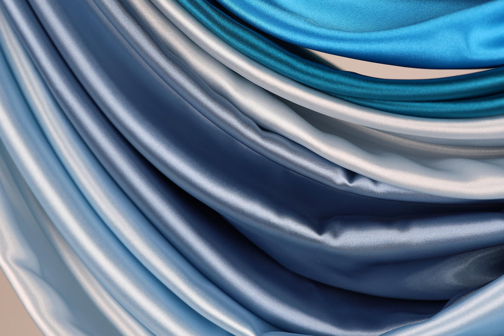 a close-up view of a collection of blue and gray satin fabric, showcasing their smooth and shiny texture.