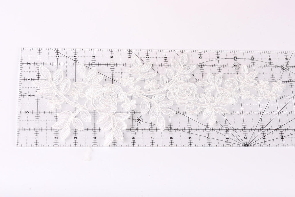 a clear ruler with a white lace pattern on it, placed on a white surface.