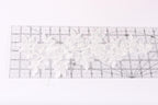a clear ruler with a white lace pattern on it, placed on a white surface.
