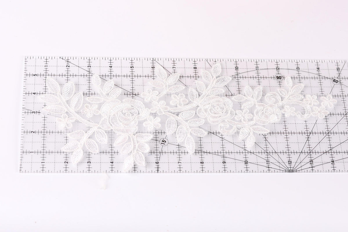 a clear ruler with a white lace pattern on it, placed on a white surface.