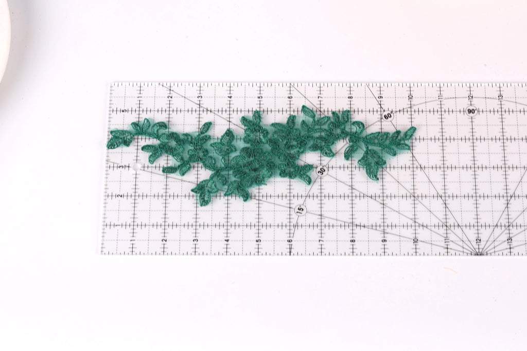 a clear ruler with a green lace-like pattern placed on it, indicating that it is being used for measuring or crafting purposes.