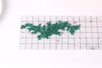 a clear ruler with a green lace-like pattern placed on it, indicating that it is being used for measuring or crafting purposes.