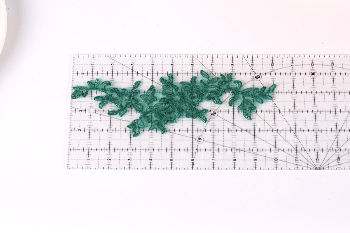 a clear ruler with a green lace-like pattern placed on it, indicating that it is being used for measuring or crafting purposes.