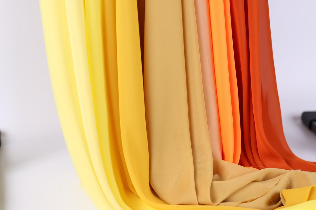 A close-up view of a collection of fabric swatches in various shades of yellow, orange, and red, arranged in a vertical line.