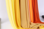 A close-up view of a collection of fabric swatches in various shades of yellow, orange, and red, arranged in a vertical line.