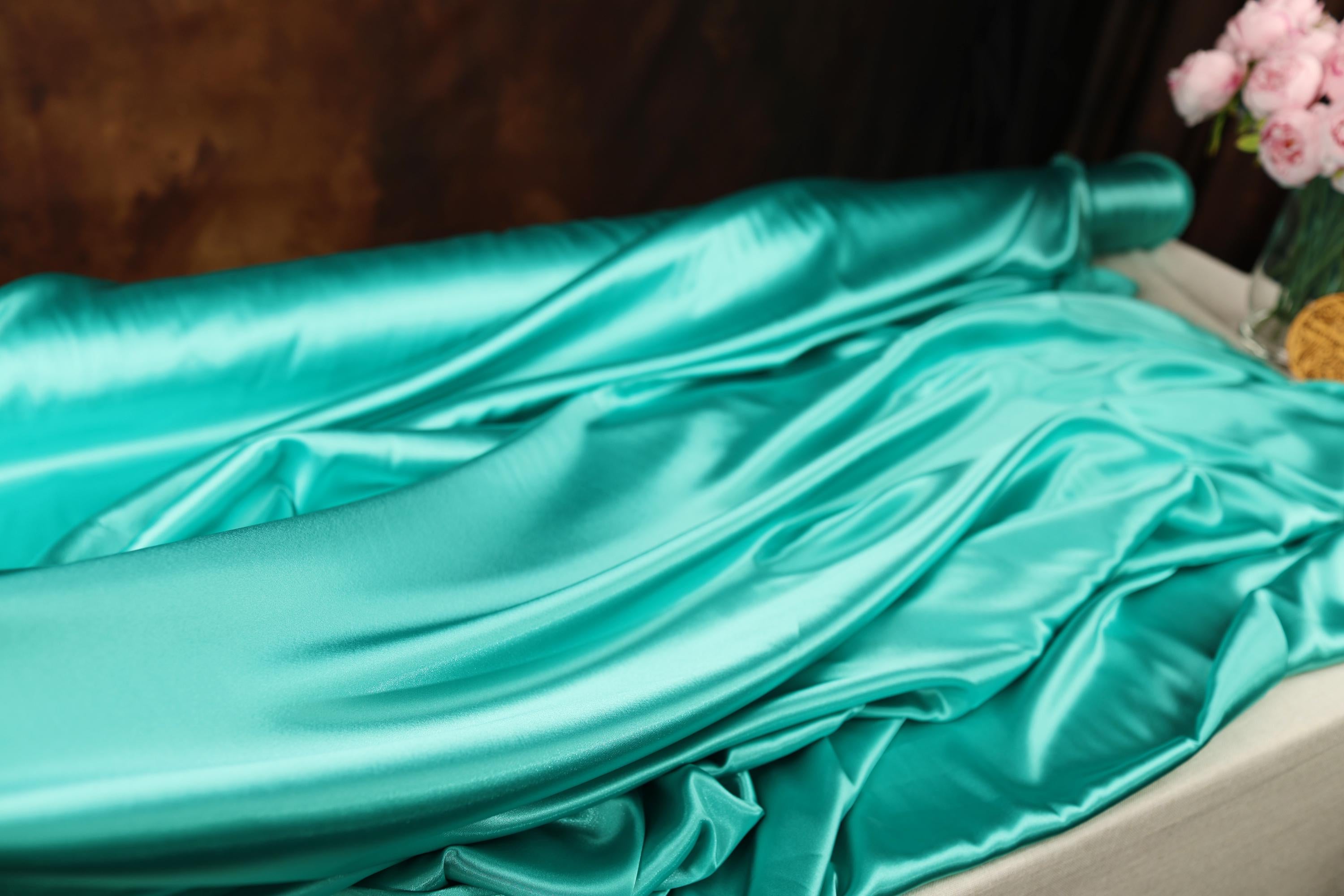 a bed with a blue sheet and a vase of flowers