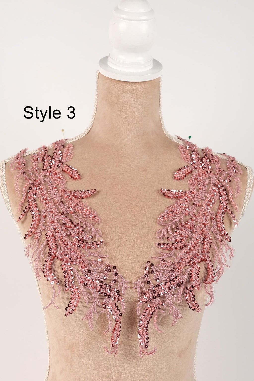 A mannequin wearing a pink sequin and lace bodice with a decorative floral pattern.