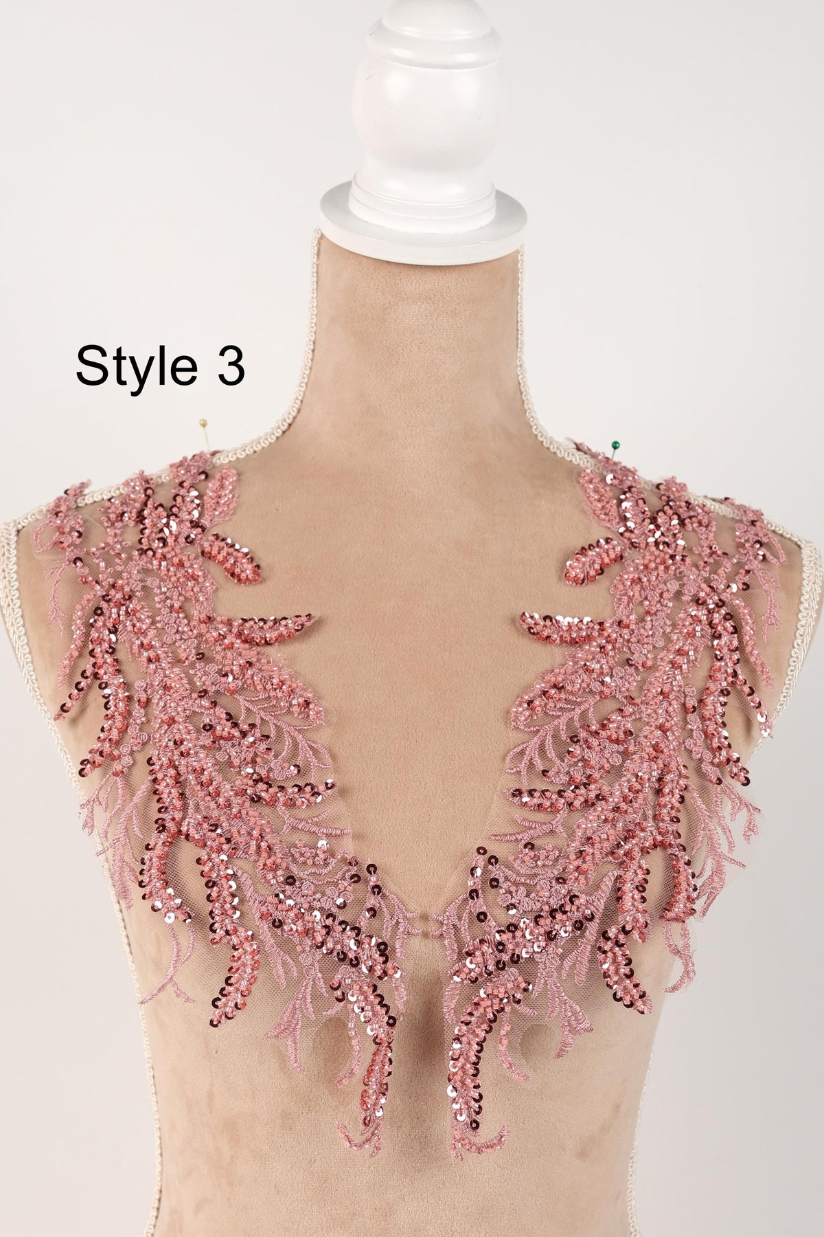 A mannequin wearing a pink sequin and lace bodice with a decorative floral pattern.