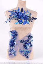 A mannequin wearing a dress with blue and purple floral embroidery and sequin accents.