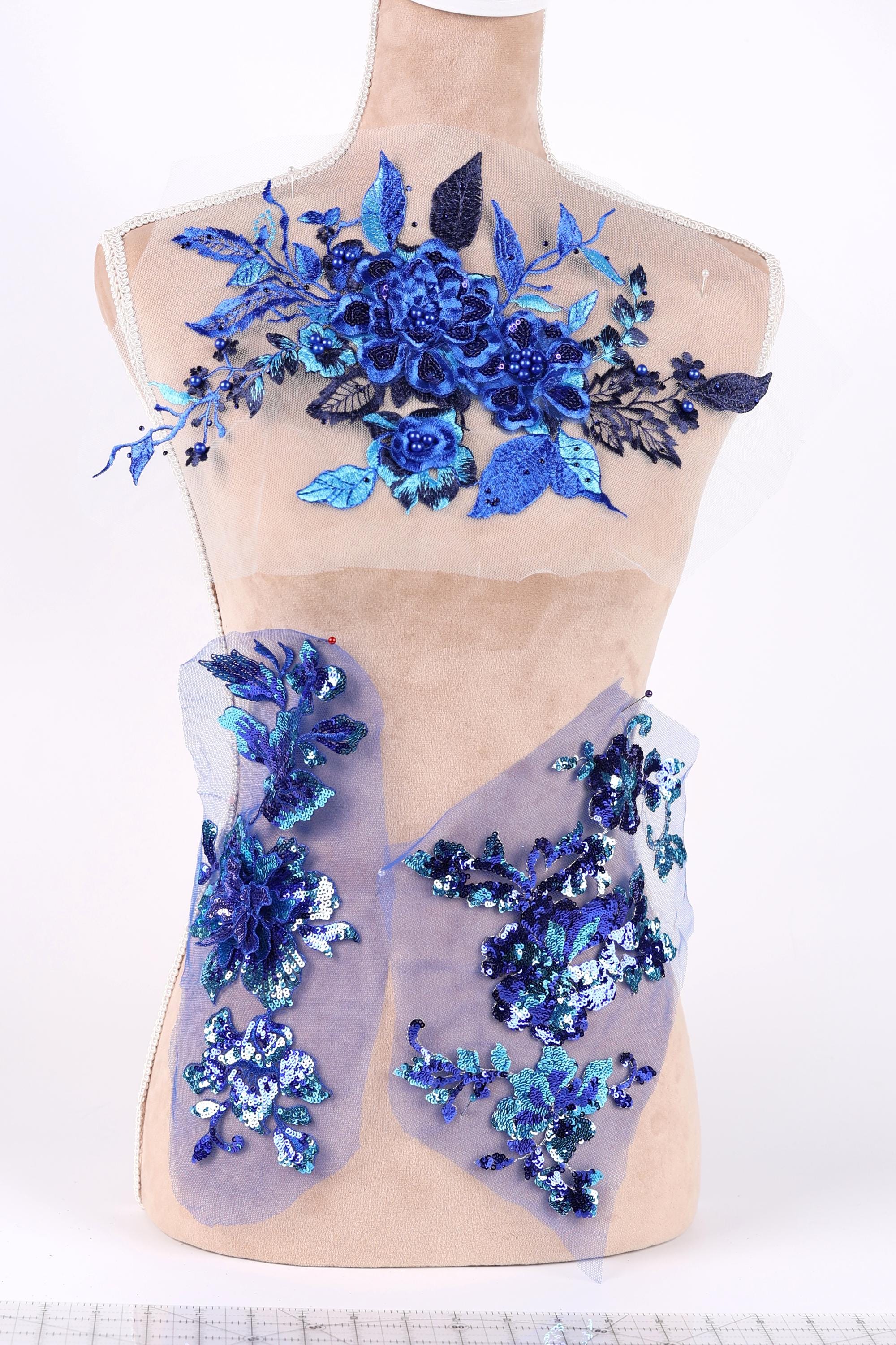 A mannequin wearing a dress with blue and purple floral embroidery and sequin accents.