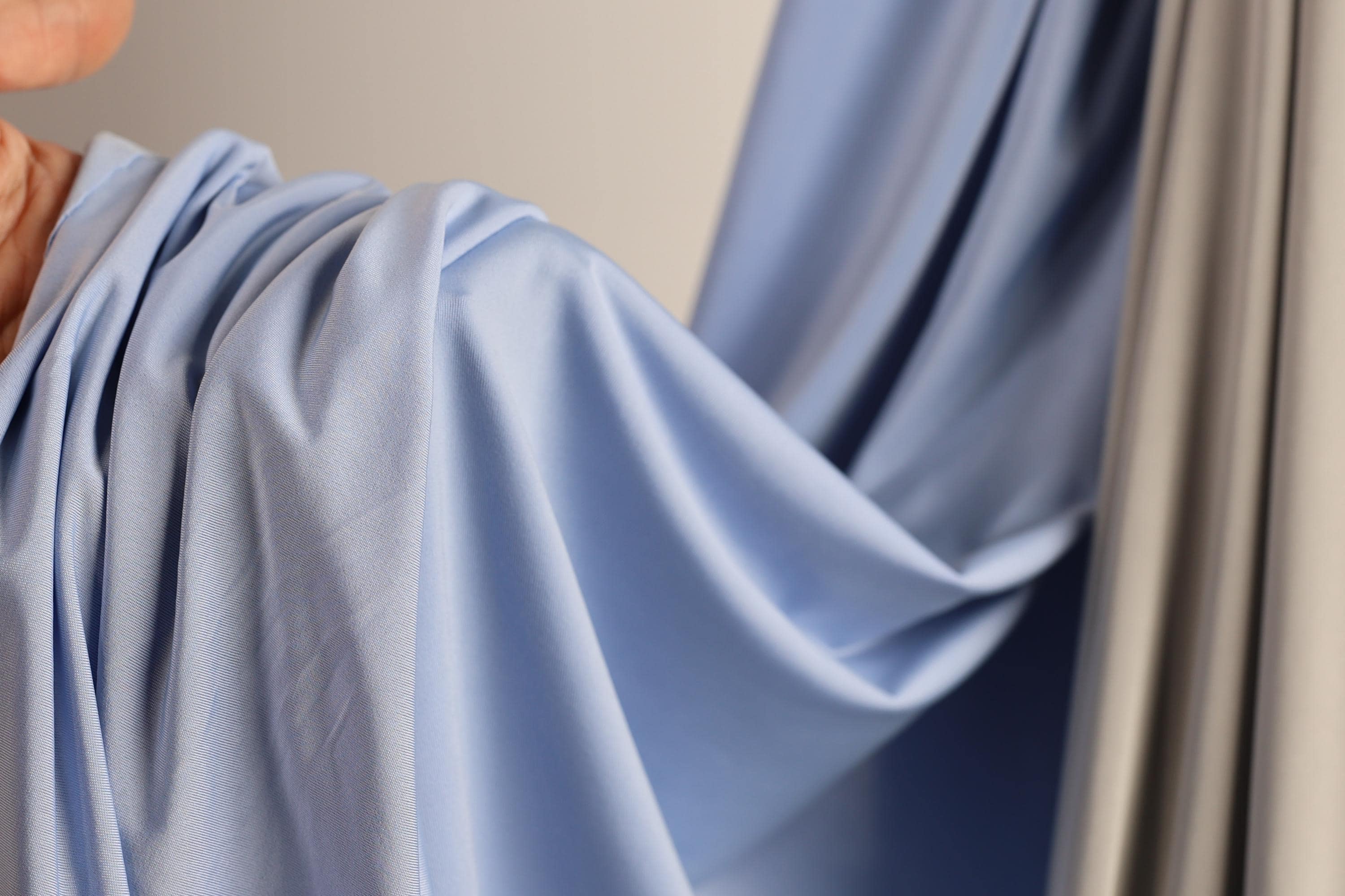 A close-up view of a blue fabric, possibly a curtain or garment, with a blurred background.