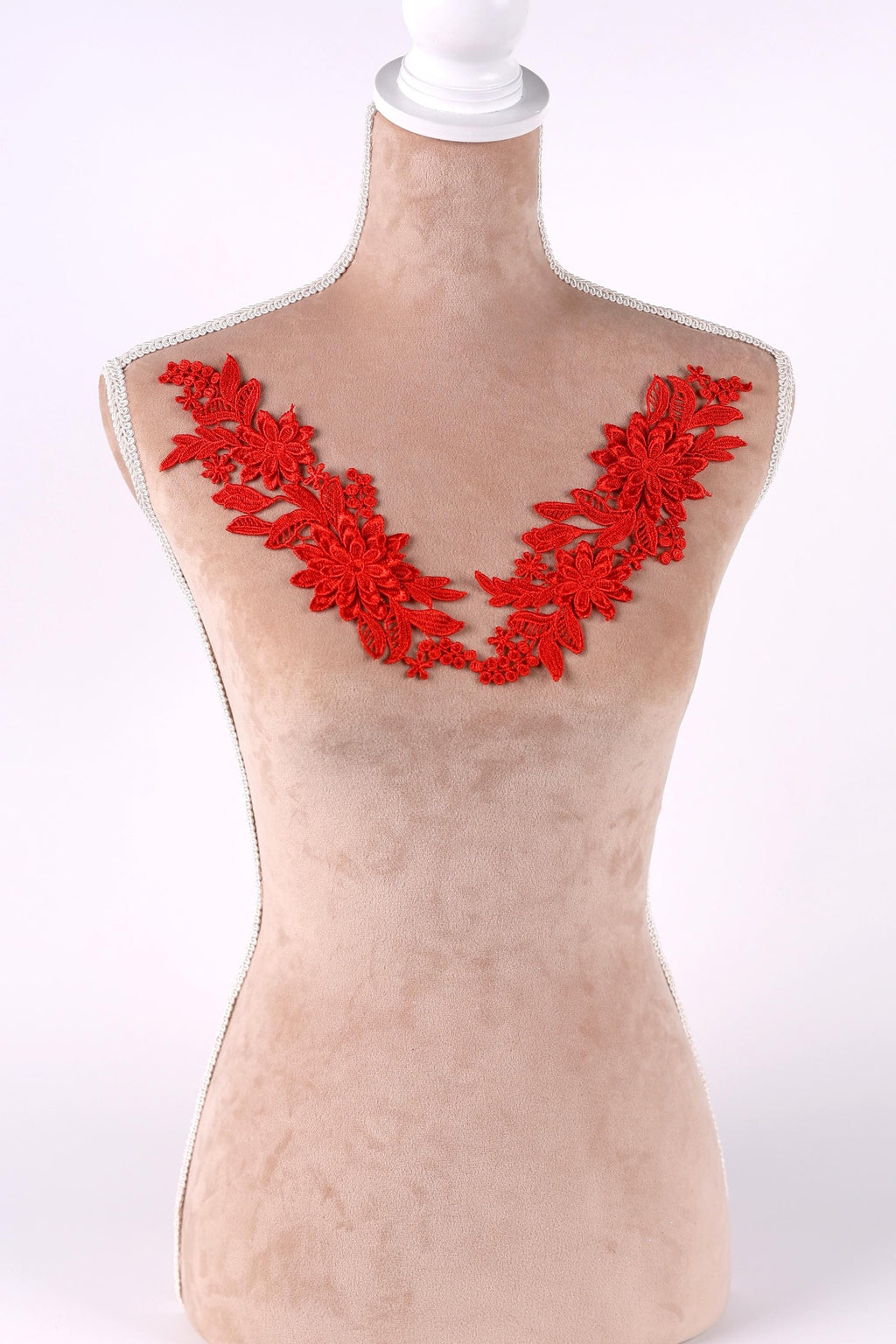 A mannequin wearing a beige dress with red floral embroidery on the bust area.