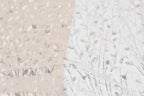 a close-up view of a fabric with a repeating pattern of silver and white sequin designs, resembling a tree or plant.