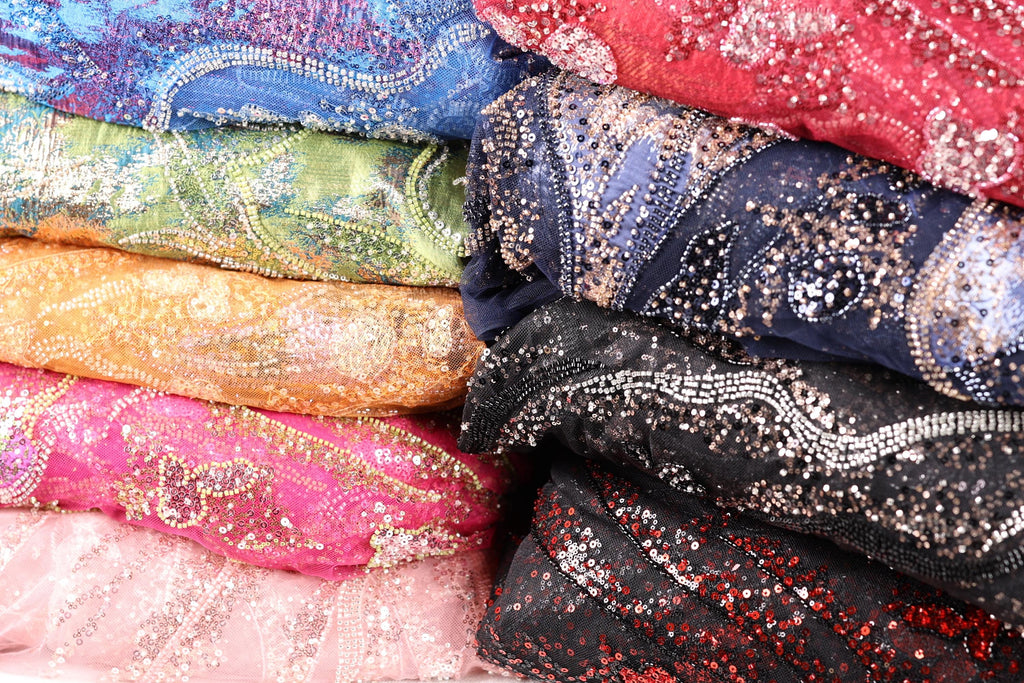 A close-up image of colorful, sequined fabric or material, with a variety of patterns and textures visible.