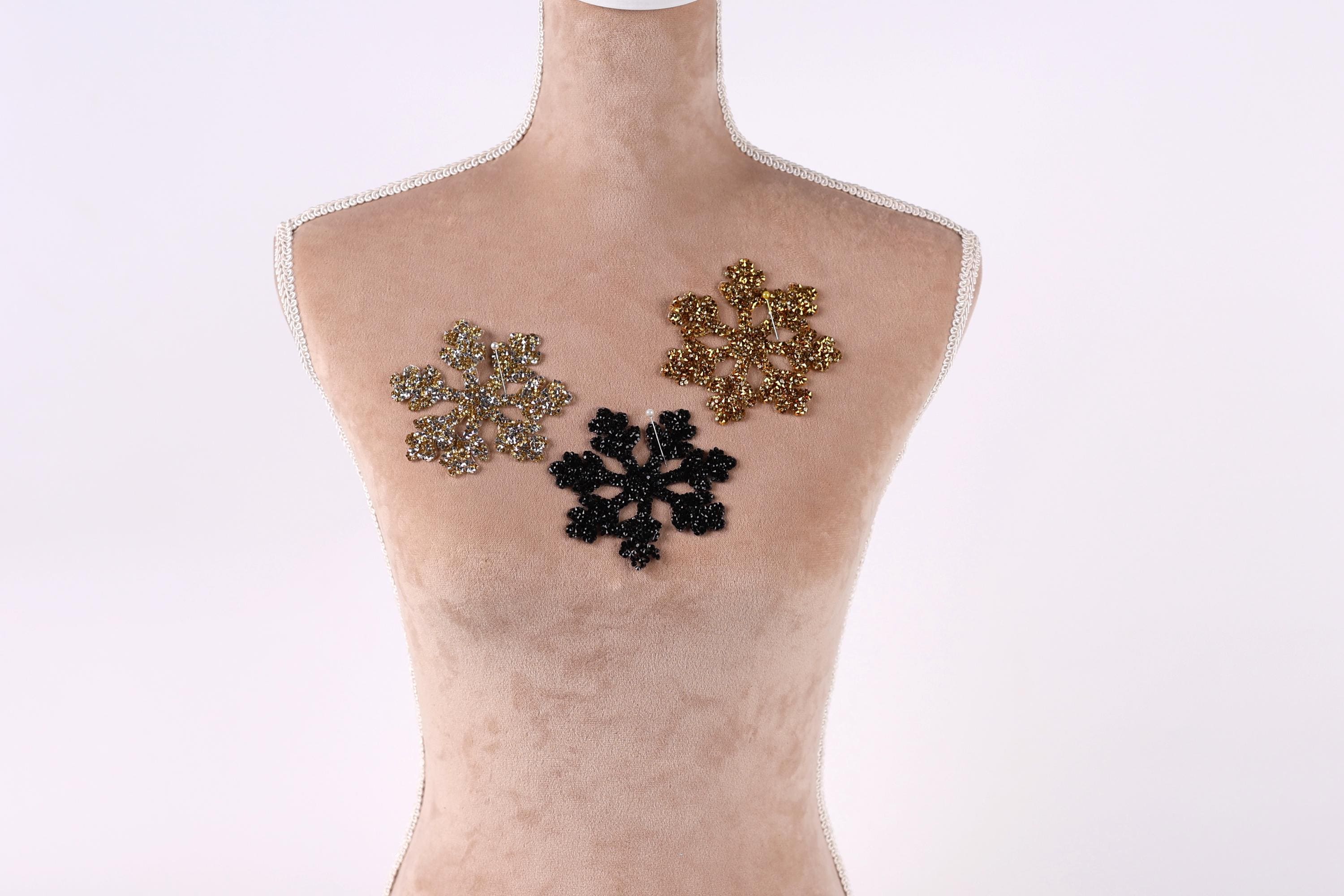A mannequin with three decorative snowflake-shaped embellishments on its bust.
