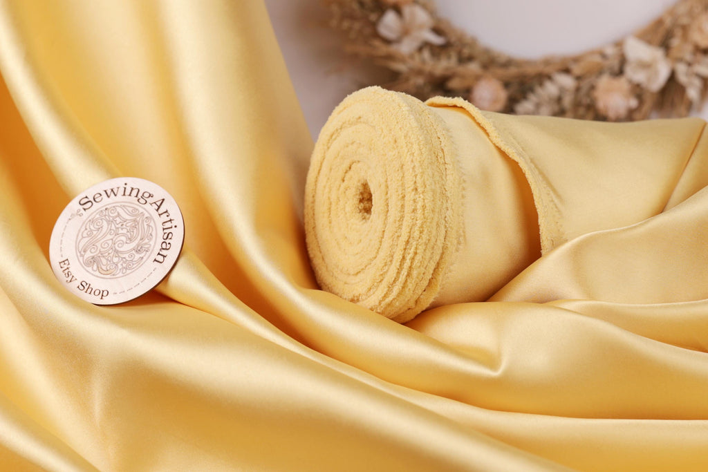 a close-up of a yellow fabric, possibly silk or satin, with a sewing-related sticker or label placed on it.
