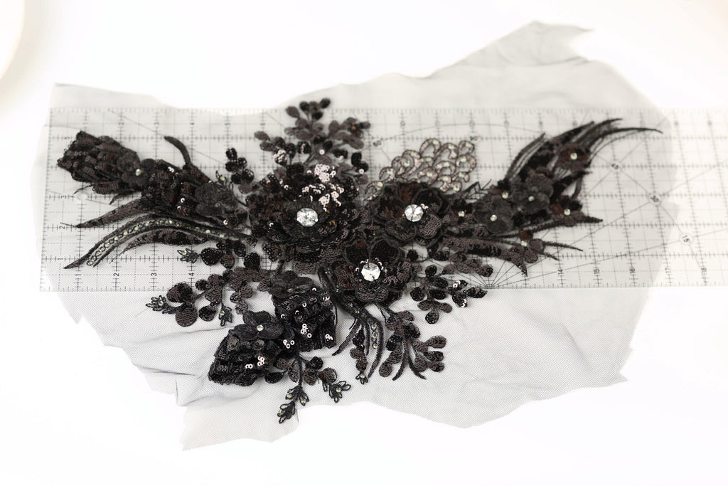 a close-up view of a black lace flower with intricate details and sparkling rhinestones.