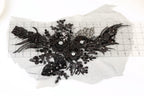 a close-up view of a black lace flower with intricate details and sparkling rhinestones.