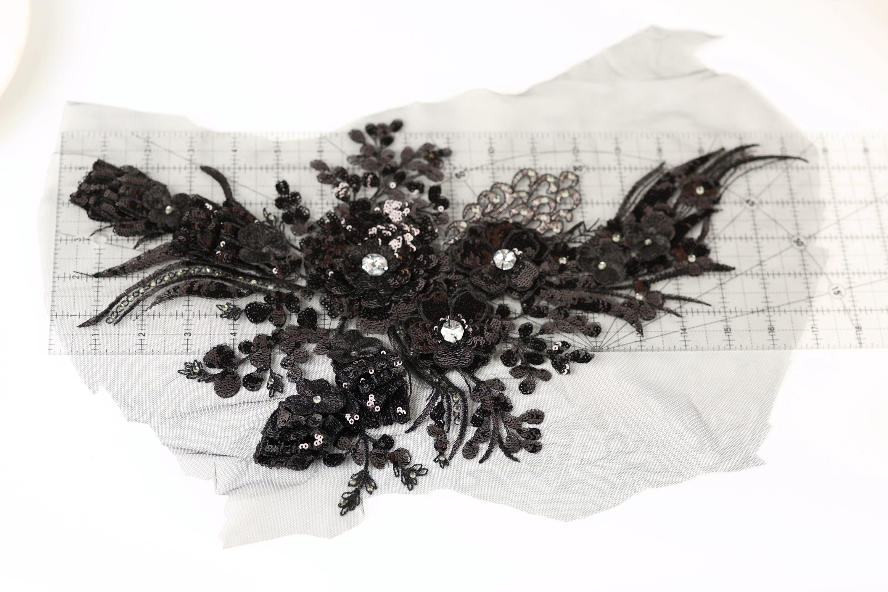 a close-up view of a black lace flower with intricate details and sparkling rhinestones.