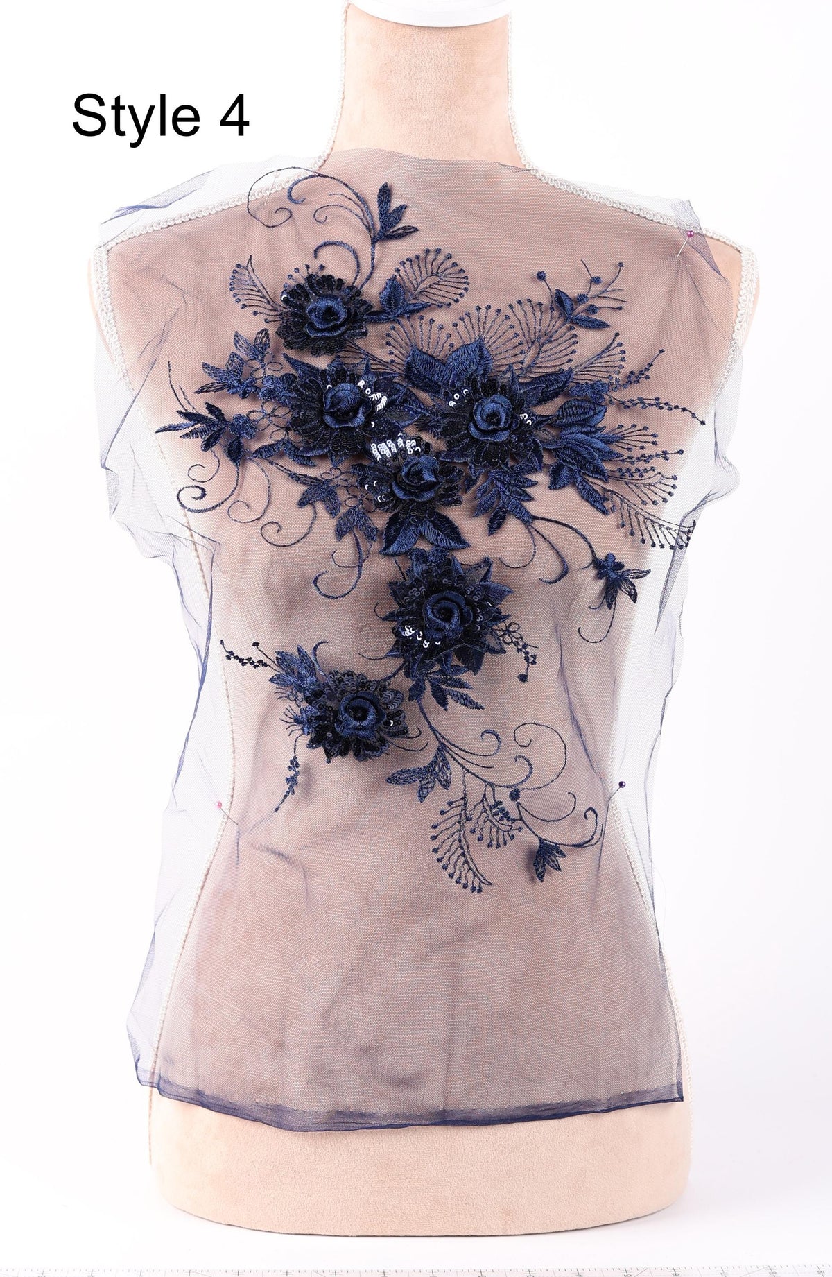 A mannequin wearing a sheer top with a floral embroidered design in navy blue on the back.