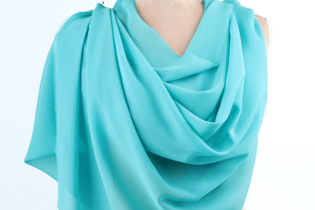 A turquoise fabric draped over a mannequin, creating a flowing, draped effect.