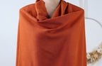 A mannequin wearing a bright orange, draped garment.