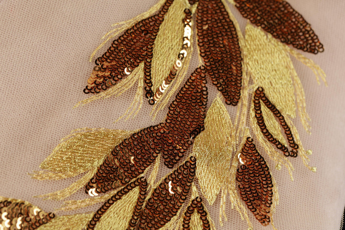 a close-up view of a delicate, intricate embroidered design with a combination of brown and gold sequins and beads. The design appears to be a floral pattern, with the individual elements meticulously arranged to create a visually appealing and detailed piece of textile art.