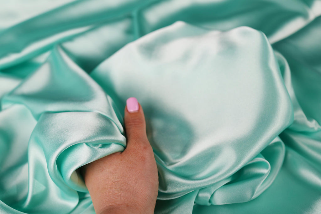 a person&#39;s hand on a satin material