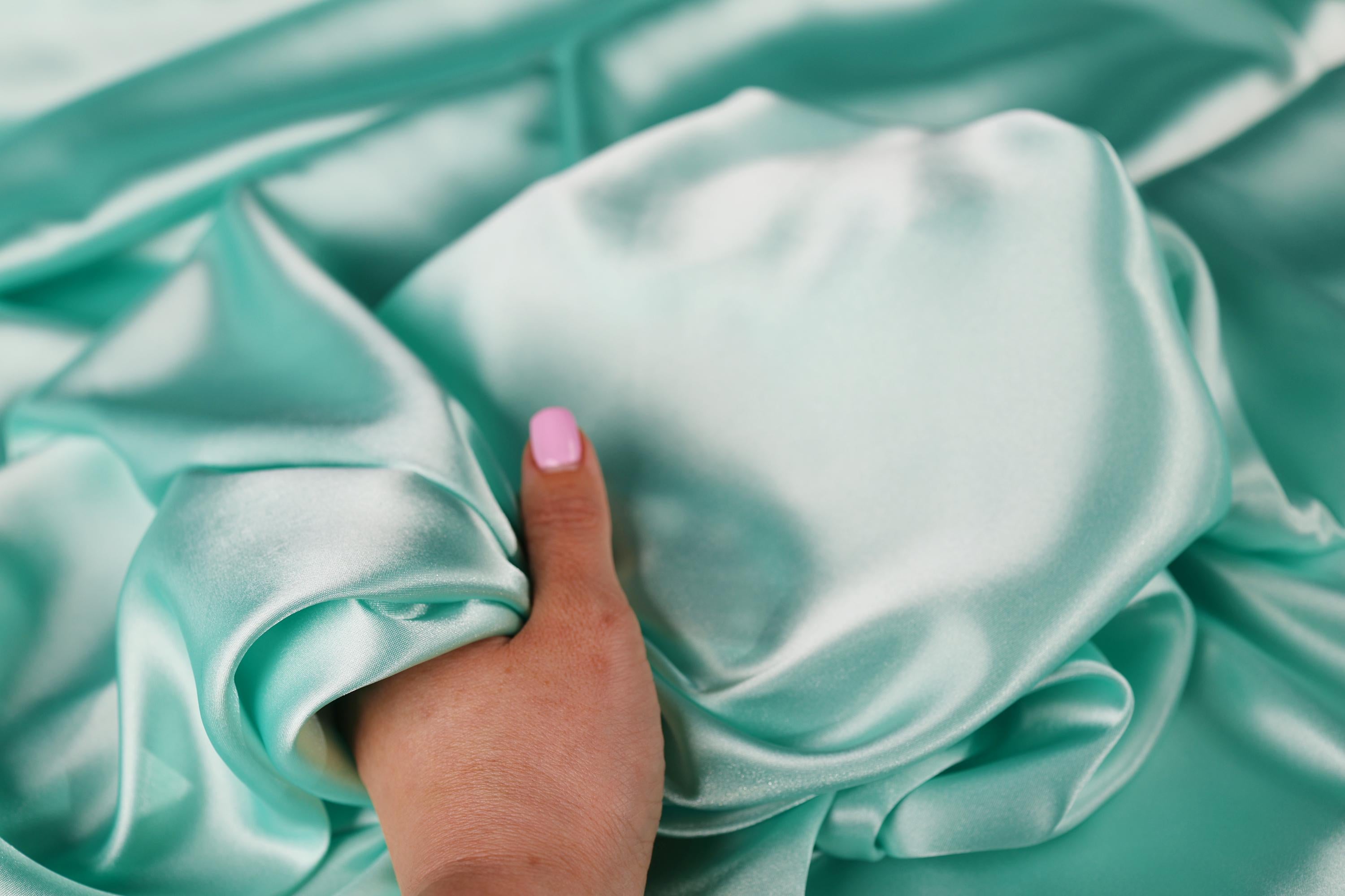 a person&#39;s hand on a satin material