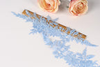 a close-up view of a delicate blue lace fabric with intricate floral patterns, placed next to a ruler on a white surface.