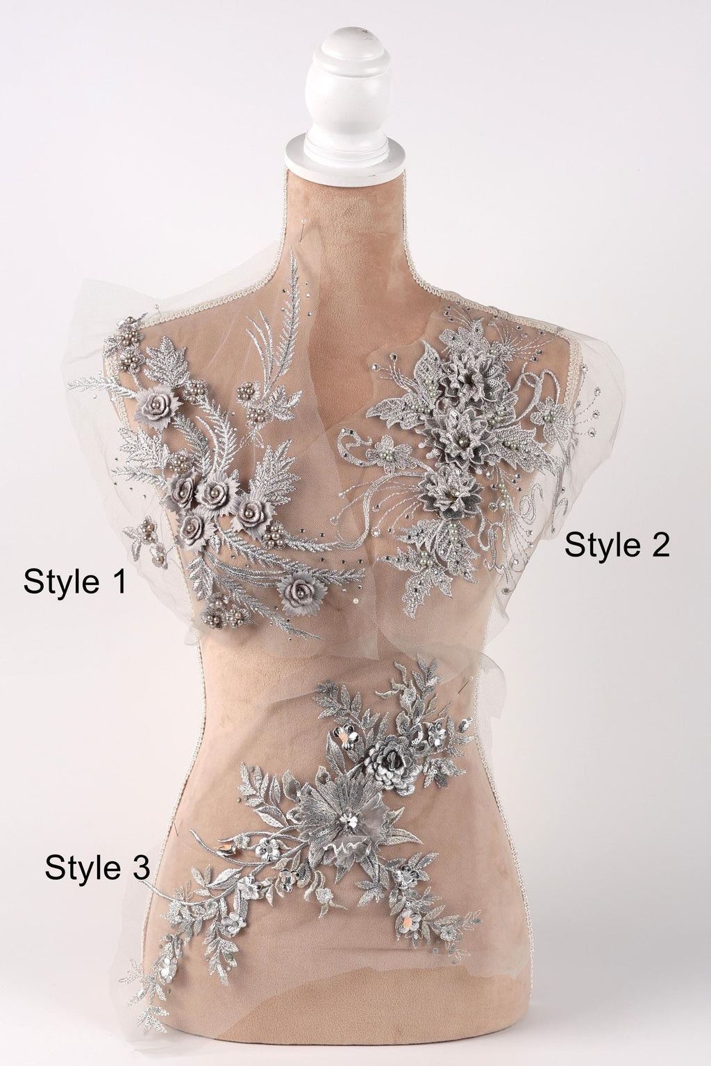 A mannequin with a beige body and a white head, adorned with silver floral and leaf designs. The mannequin is positioned in a way that allows for a clear view of the intricate details of the embellishments.
