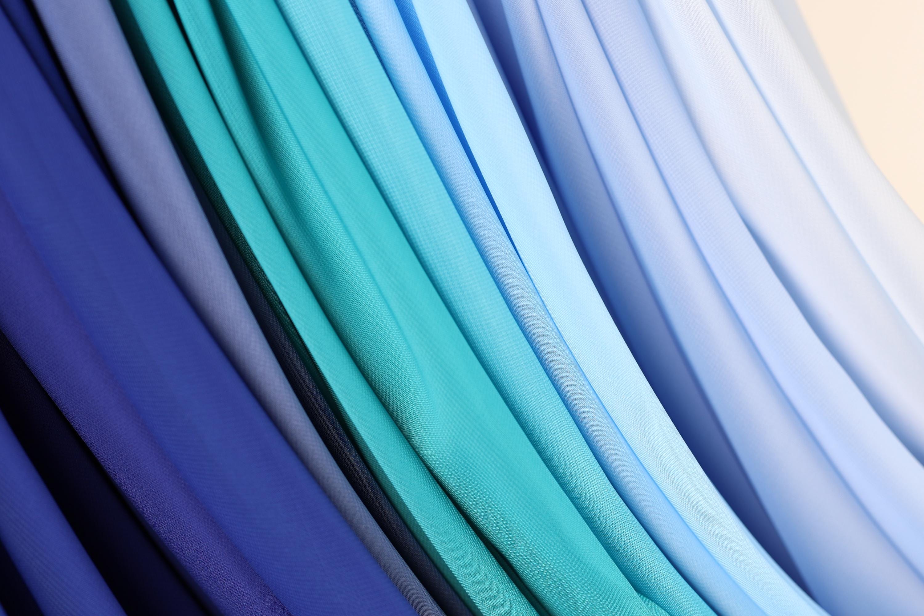 a close-up view of a collection of fabric swatches in various shades of blue, including light blue, dark blue, and a darker shade of blue.