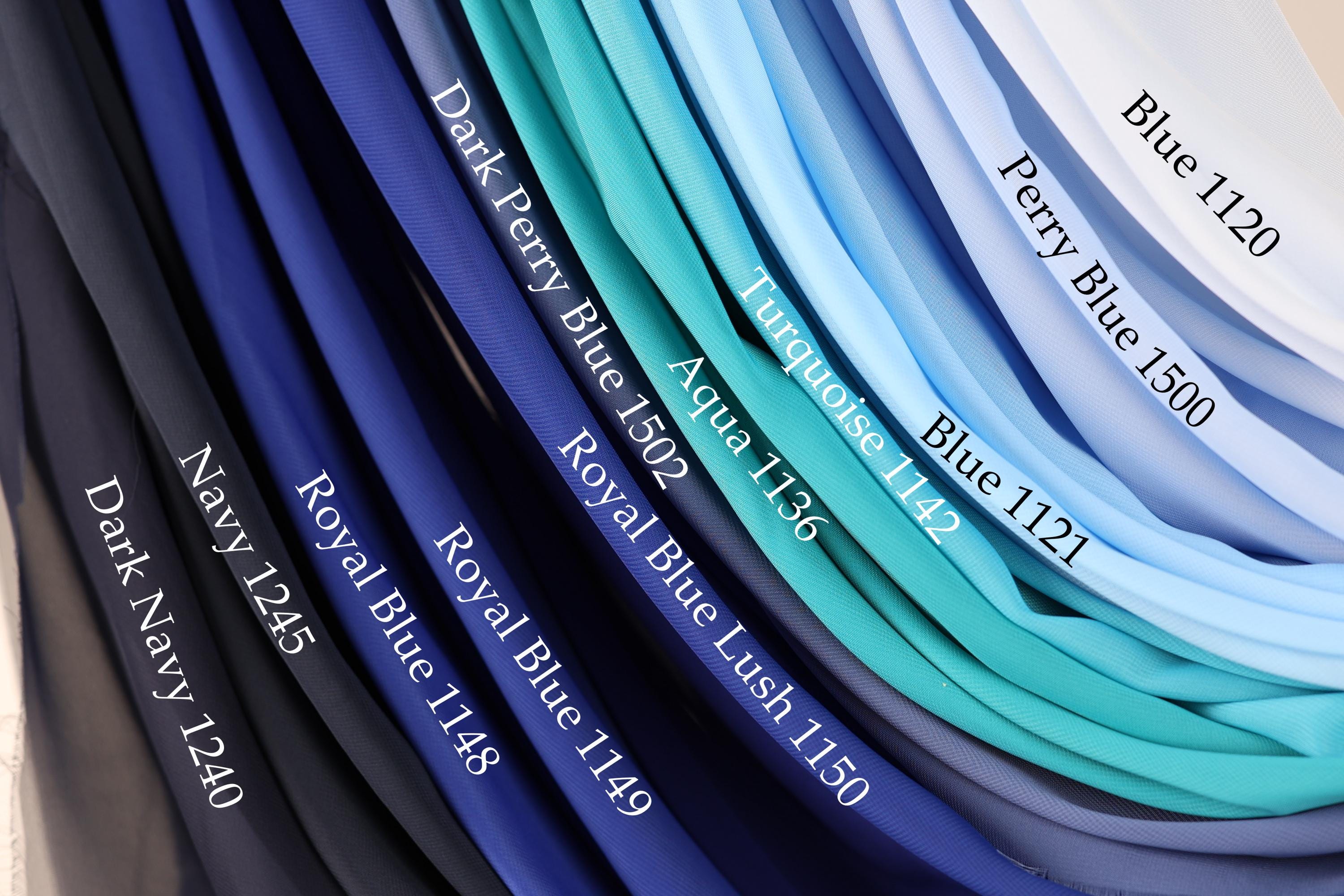 A collection of fabric swatches in various shades of blue, including navy, royal blue, turquoise, aqua, and light blue, with labels indicating the color names and numbers.